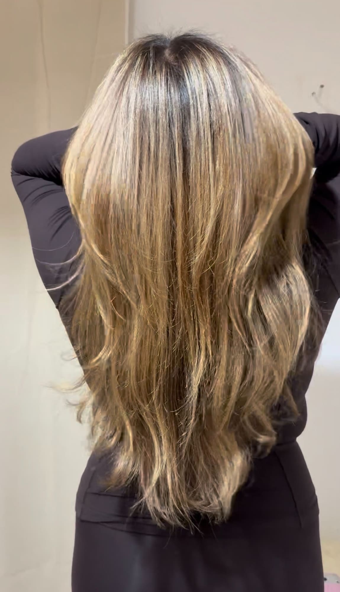 Long layered blonde hair with highlights shown from back view