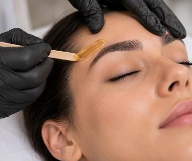 Professional applying eyebrow tint with brush to client's forehead